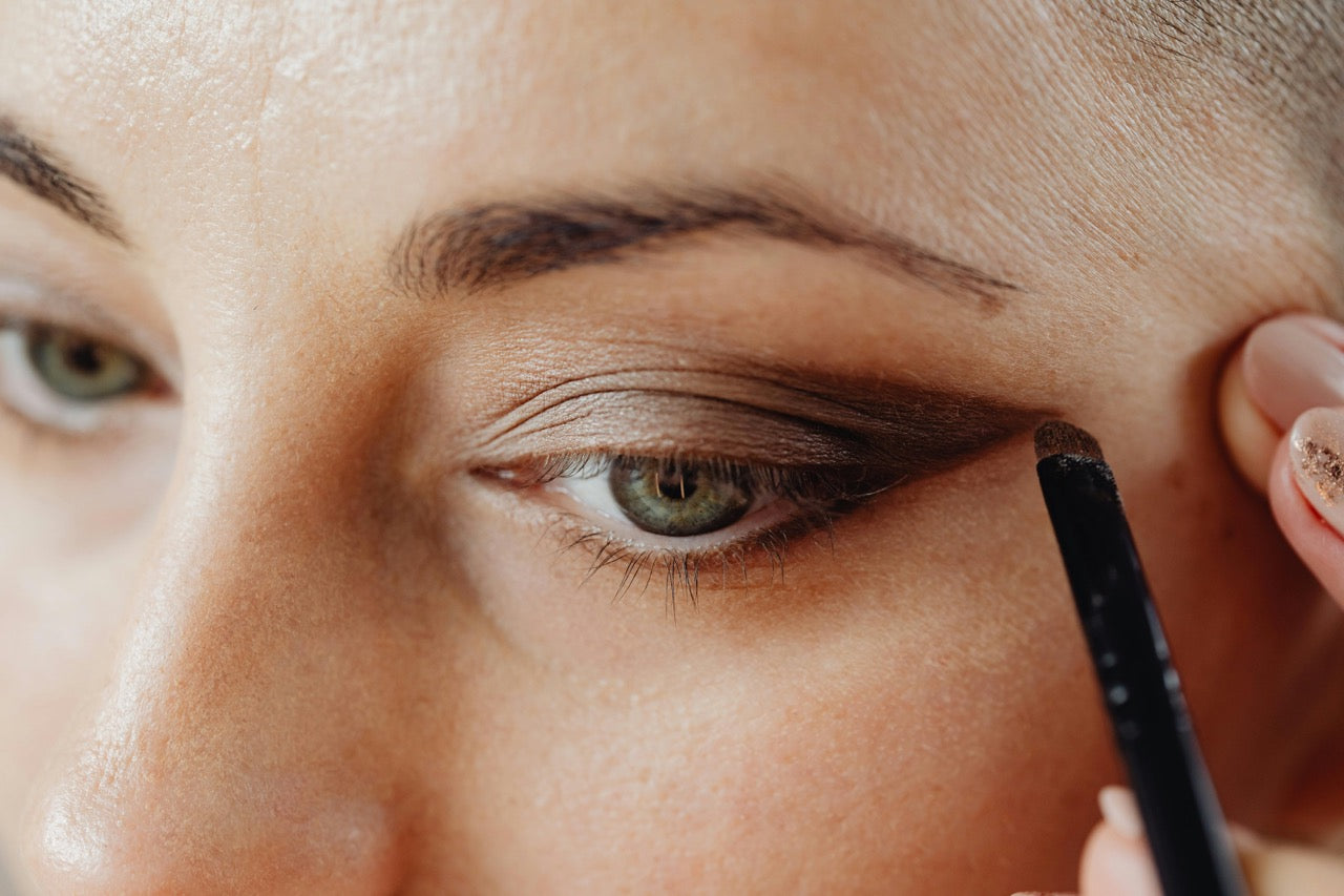 Close-up of a person applying makeup to their eye with a brush.