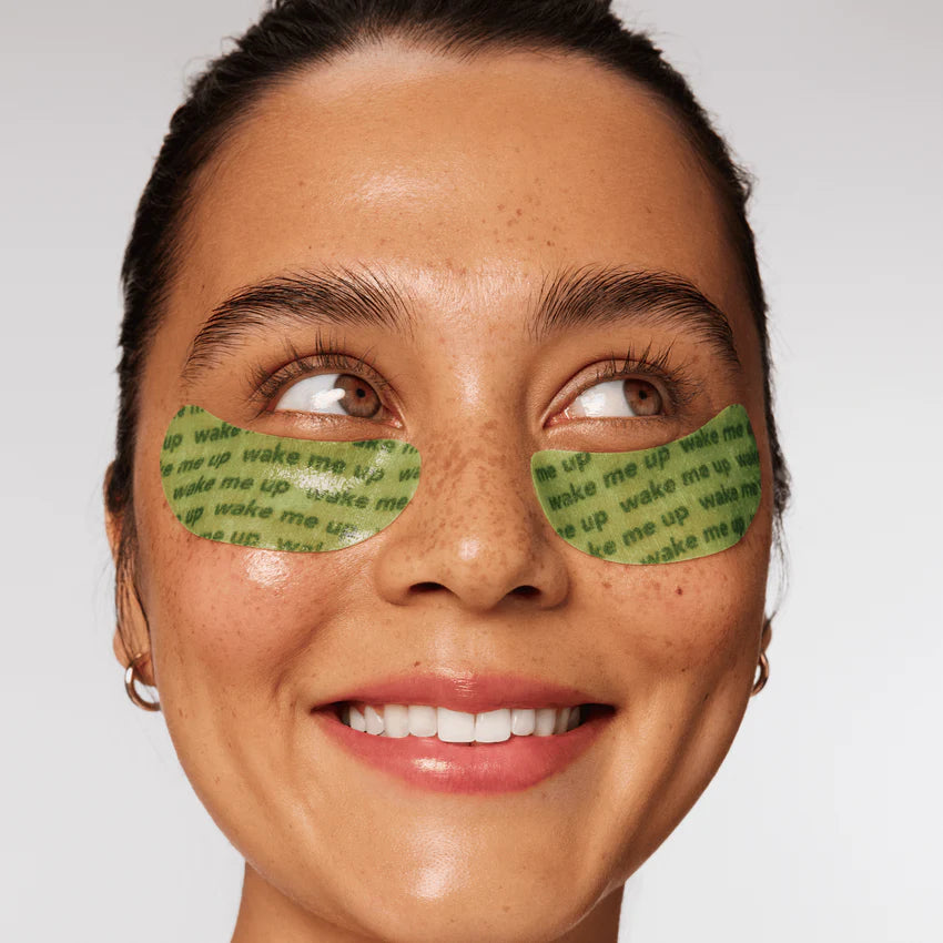Woman wearing green eye masks with text on a plain background