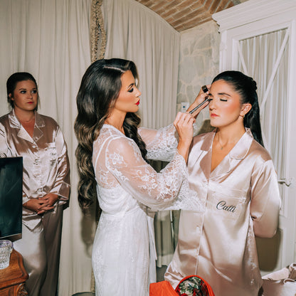 Two women getting ready in a room with a brick wall and white curtains.