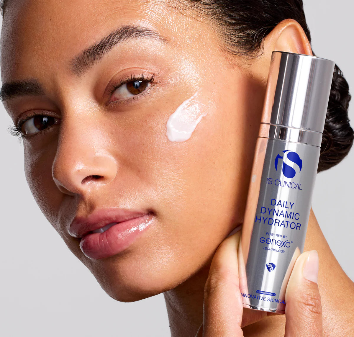 Woman applying skincare product to her face with a focus on the bottle labeled 'Clinical Daily Dynamic Hydrator'.