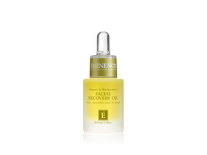 Facial recovery oil bottle with green cap on a white background