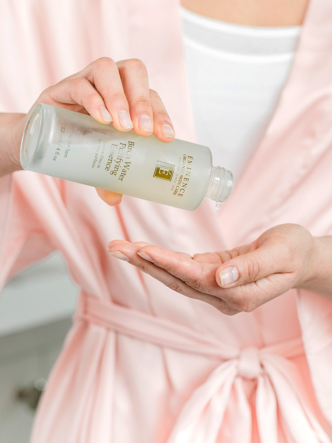 Person applying a skincare product from a bottle labeled 'Biore' on their palm.