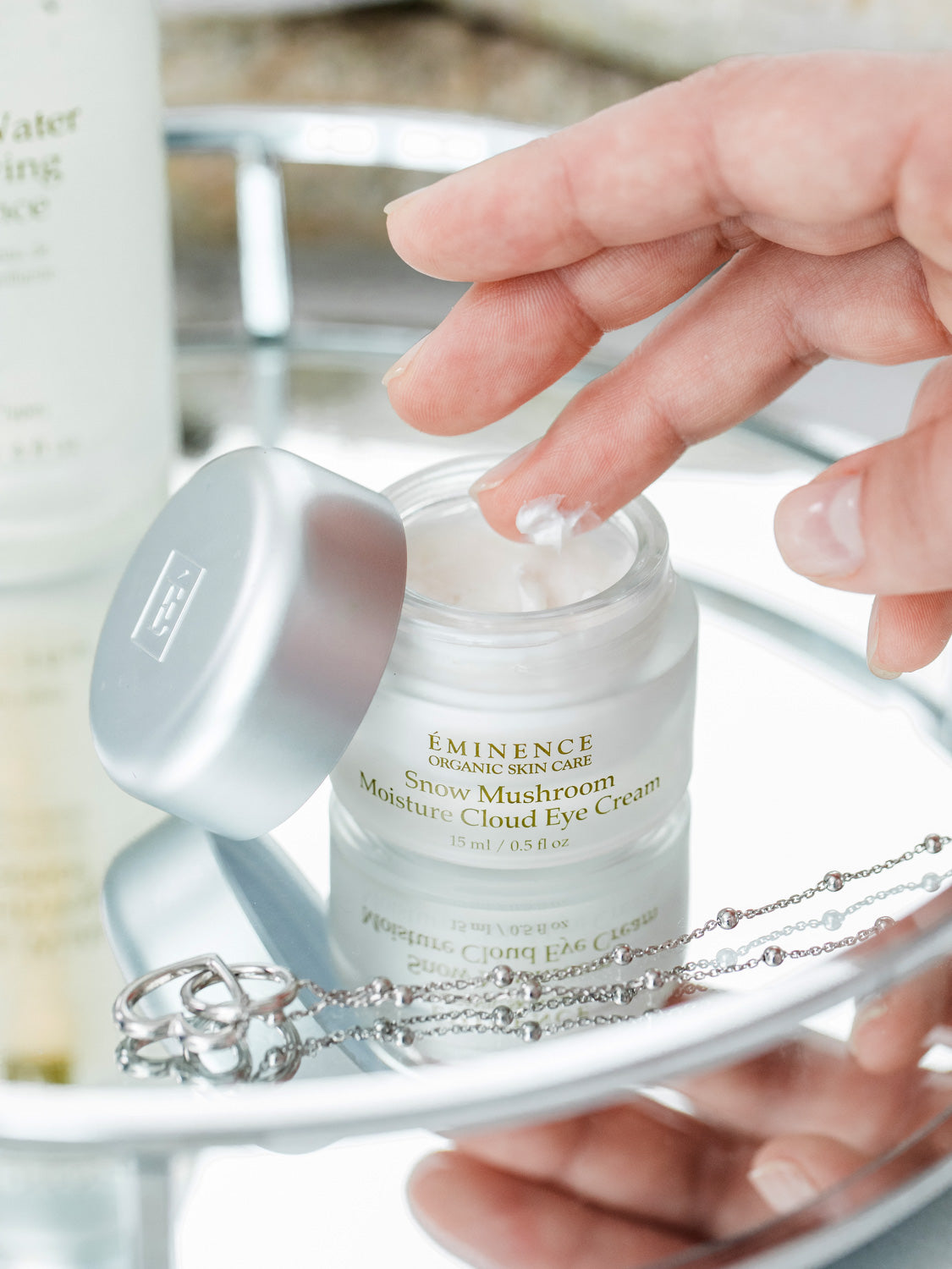 Eminence skincare cream on a tray with a hand reaching for it