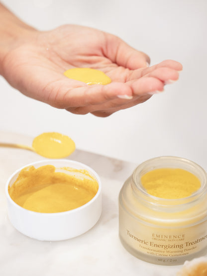 Turmeric powder in a jar and on a spoon with a hand holding a small amount.