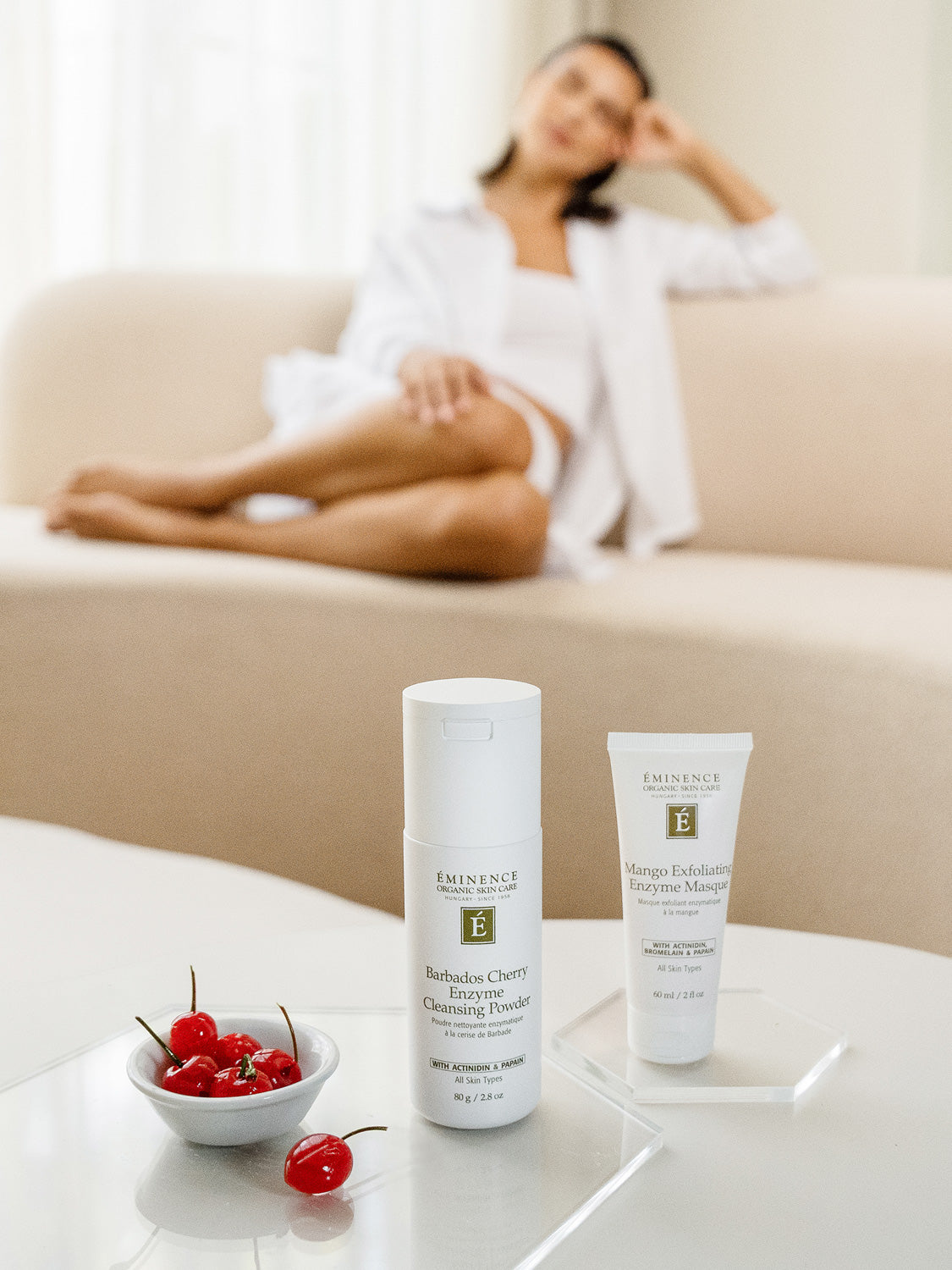 Two skincare products on a table with a blurred person in the background