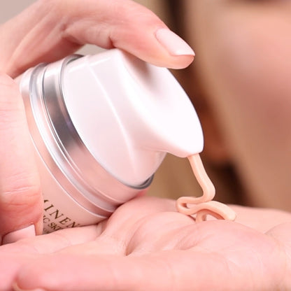 Hand applying cream from a white jar with a blurred background