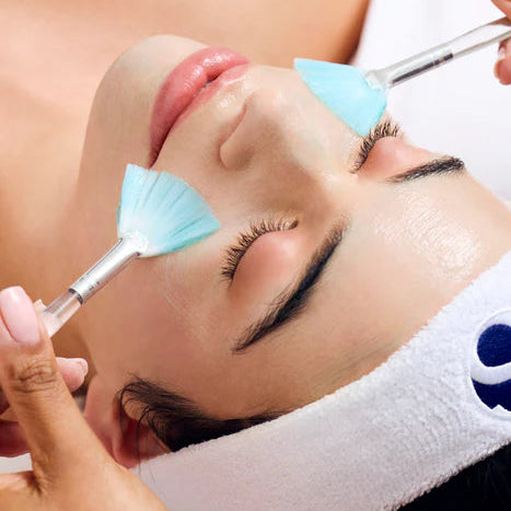 Person receiving a facial treatment with blue applicators on a blurred background