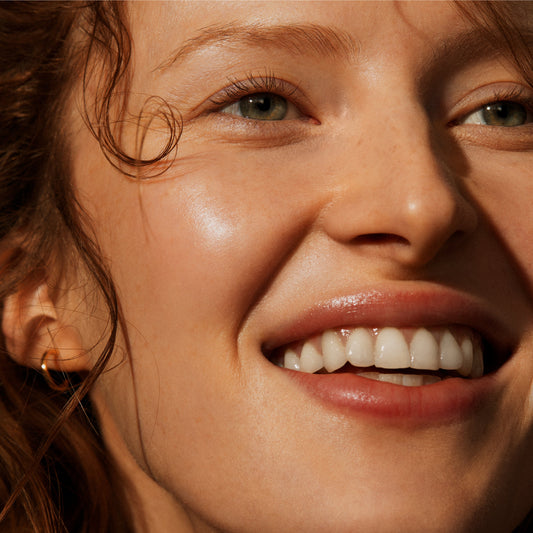 Smiling woman with glowing skin, from Irene Forte's Apricot Penta-Acid Polish imagery