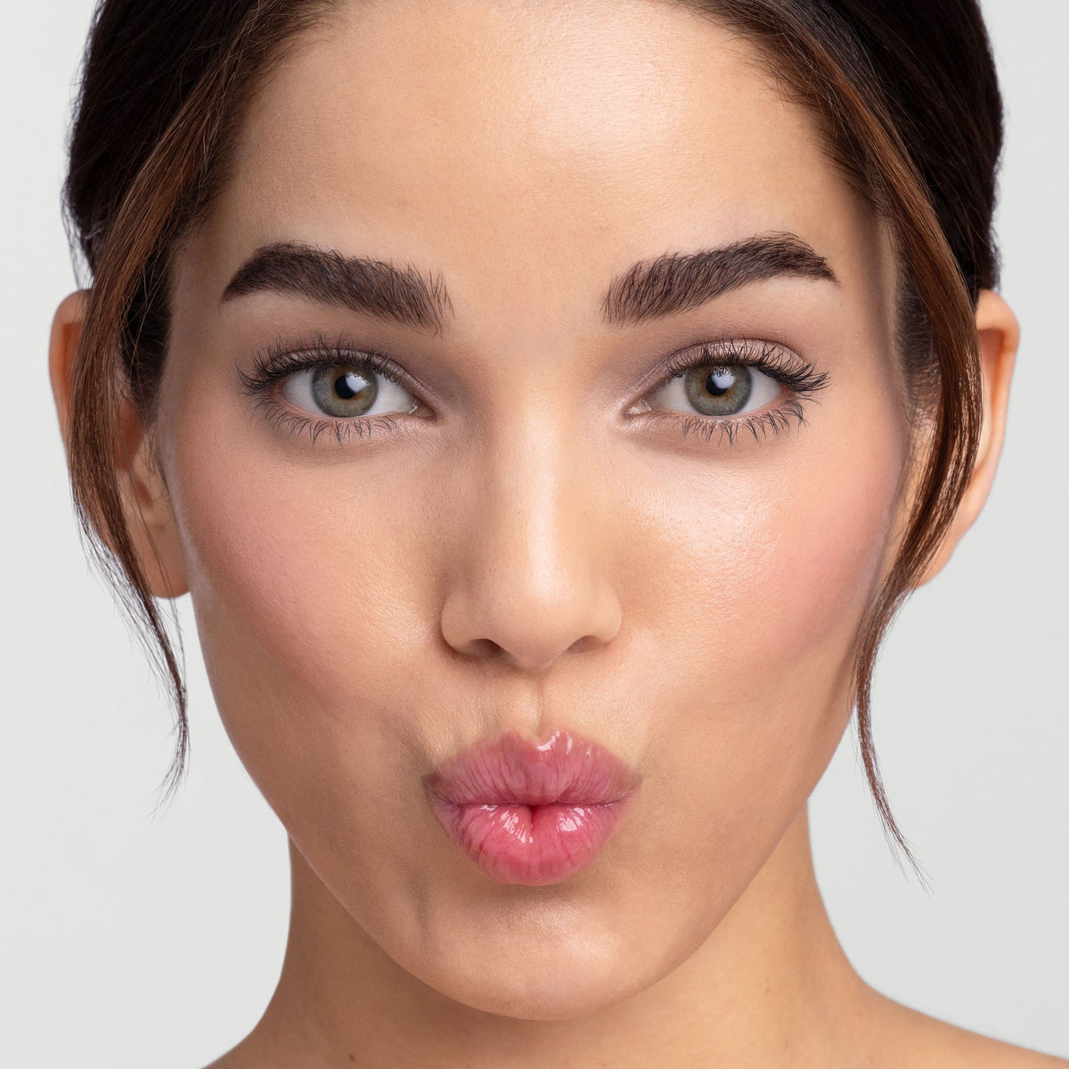 Model wearing Jane Iredale Just Kissed pH Lip Oil, lips pursed in a kiss.