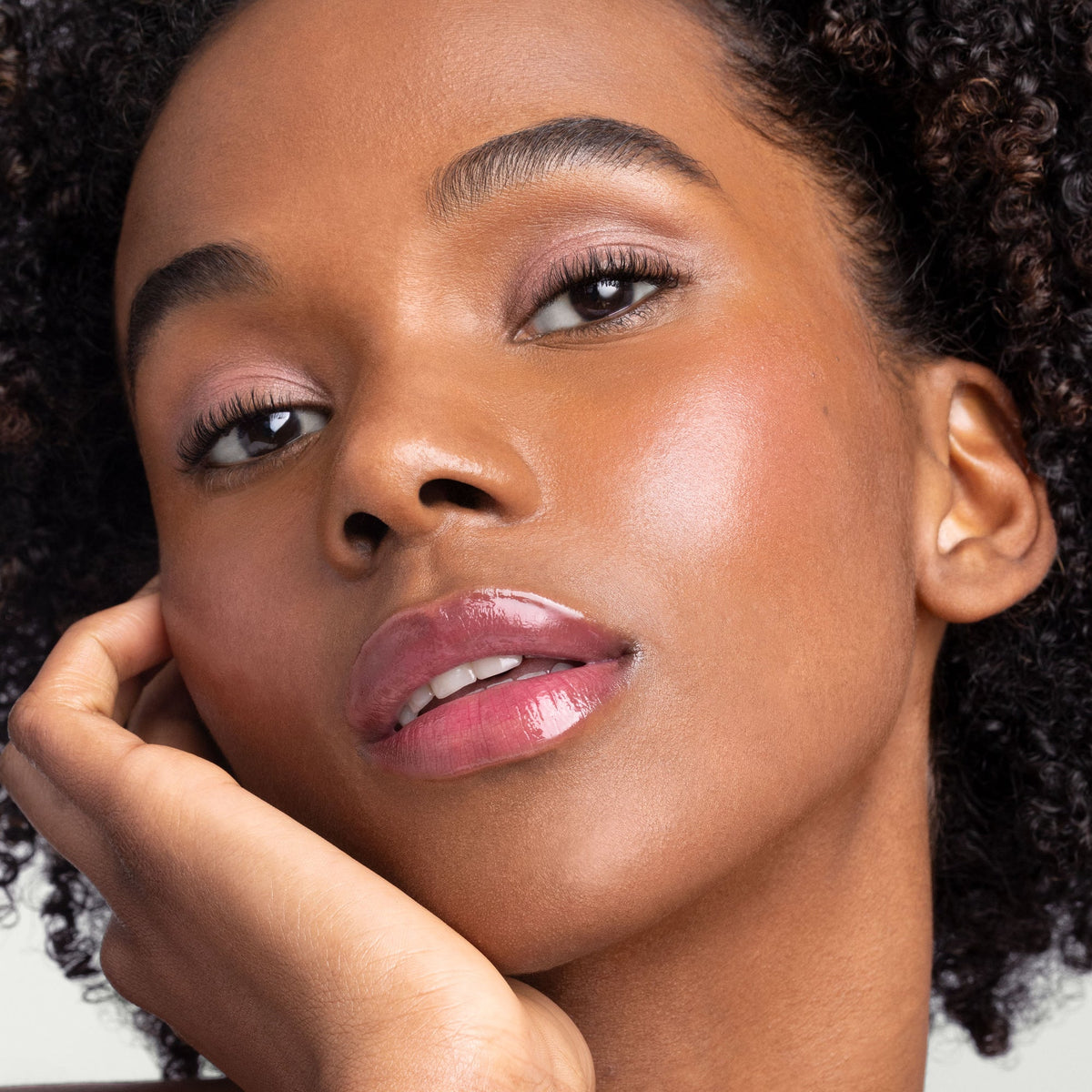 Model with deeper skin wearing Jane Iredale Just Kissed pH Lip Oil.