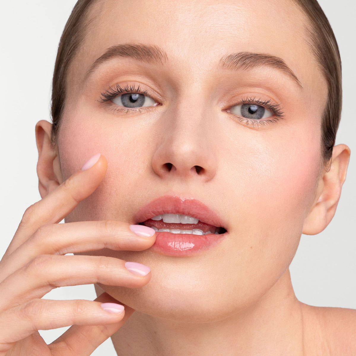 Model touching her lips while wearing Jane Iredale Just Kissed pH Lip Oil.