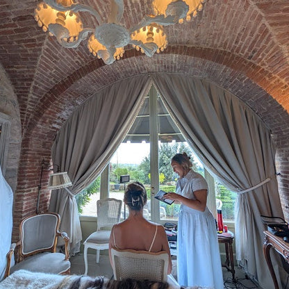 Woman in a white dress standing in a room with arched brick ceilings and large windows.
