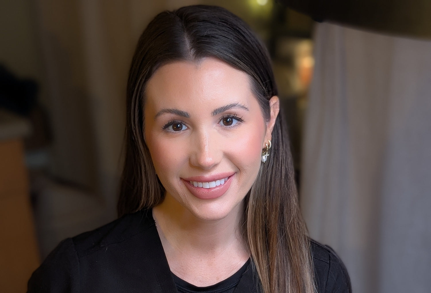 Woman holding a blue object and a small white tool in a blurred indoor setting