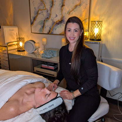 Woman performing a facial treatment on a client in a spa setting.