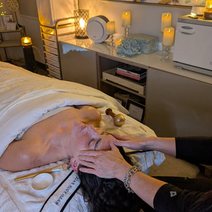 Person receiving a facial treatment in a spa setting with candles and relaxation items.