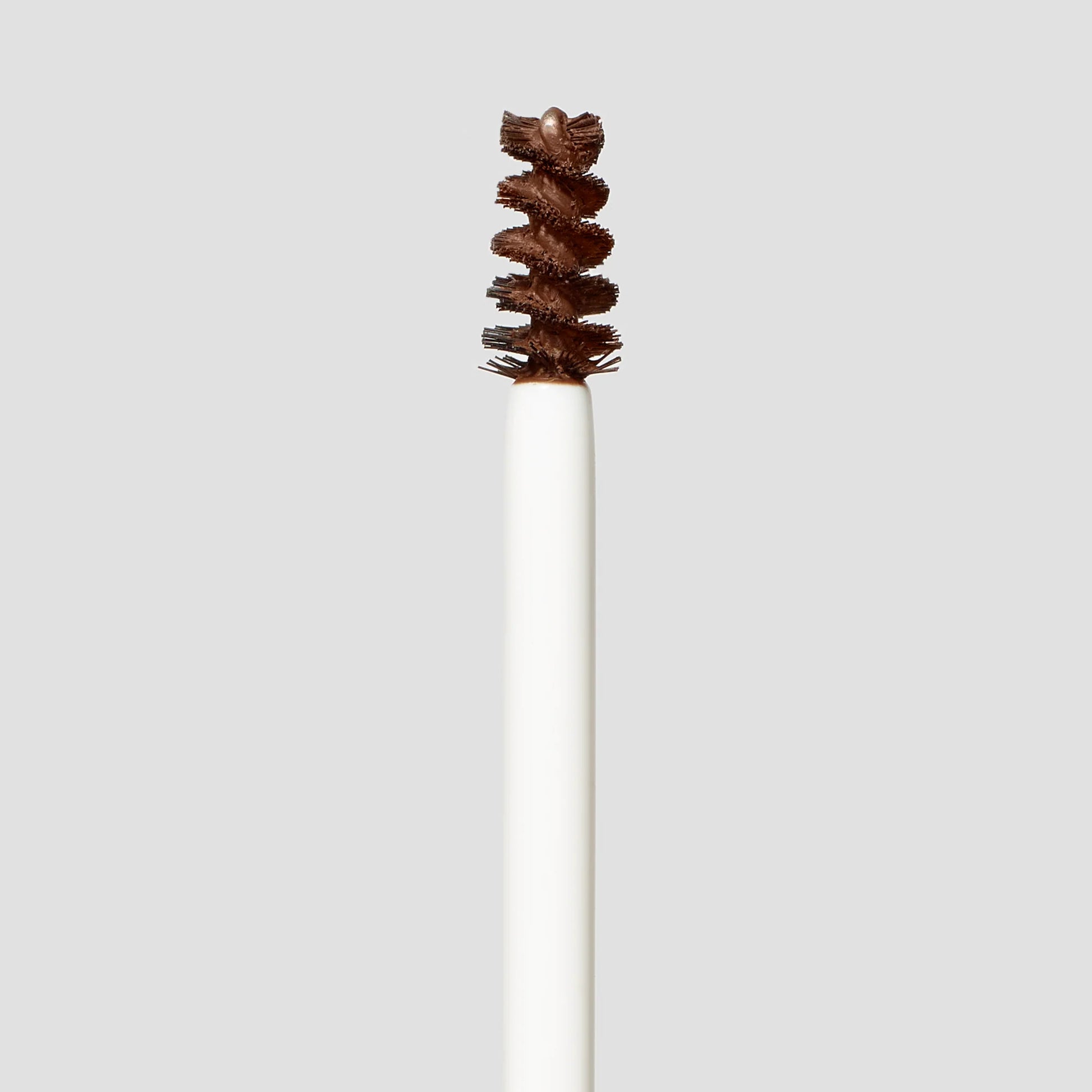White makeup brush with brown bristles on a light gray background