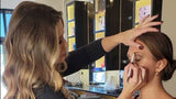 Makeup artist applying makeup to a model in a salon setting