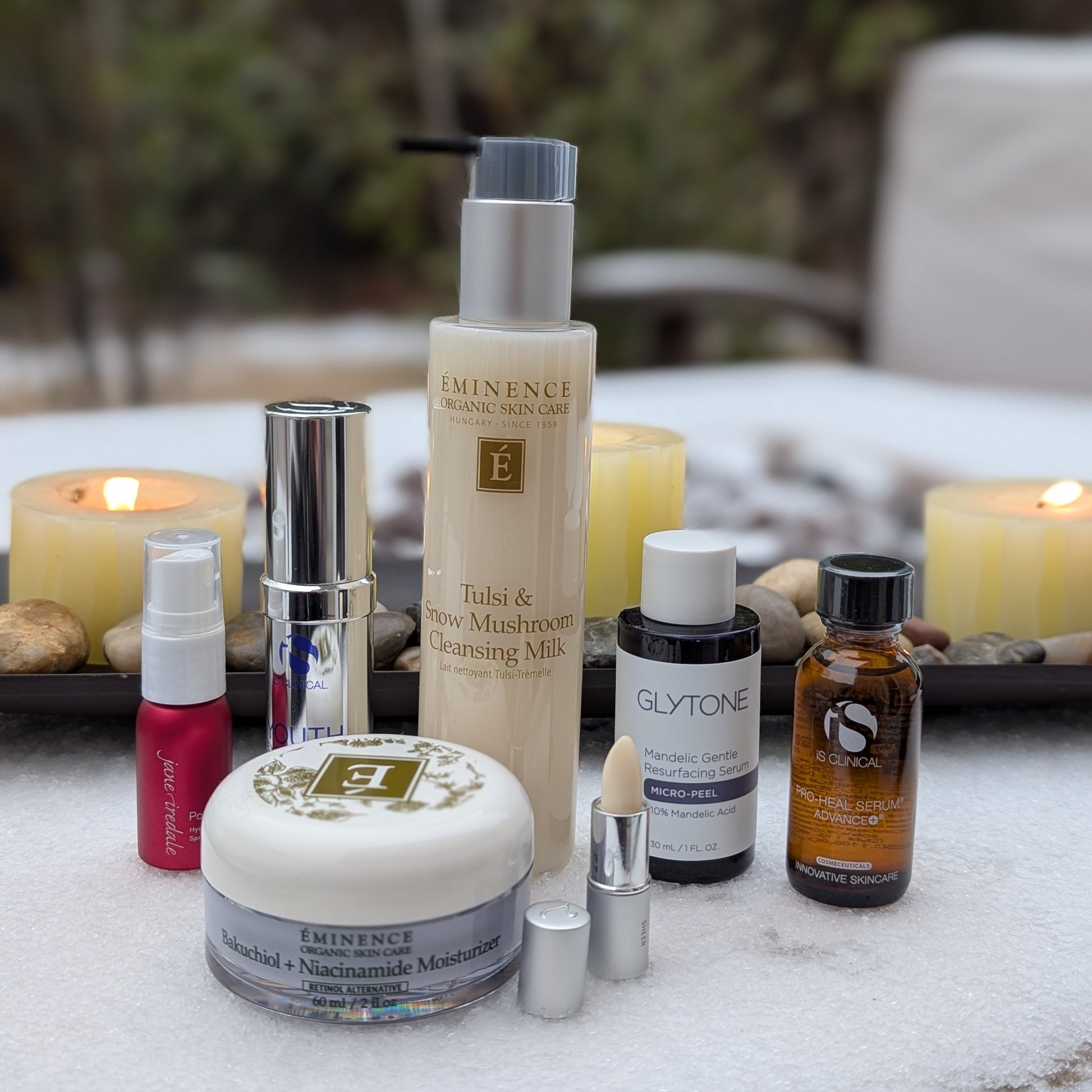 Collection of skincare products on a table with candles in the background