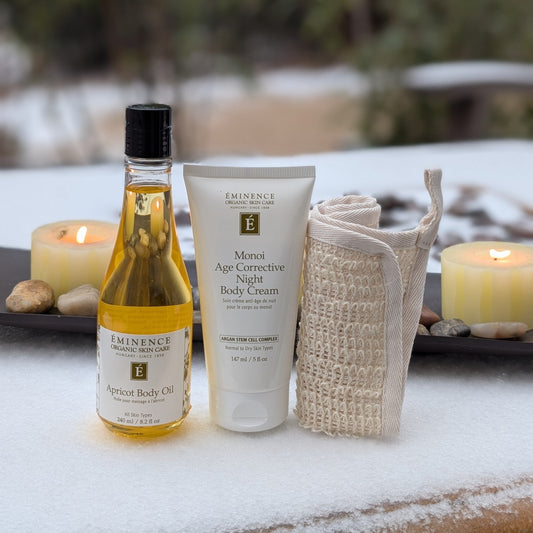 Cosmetic products including a bottle and tube on a snowy surface with candles and stones.