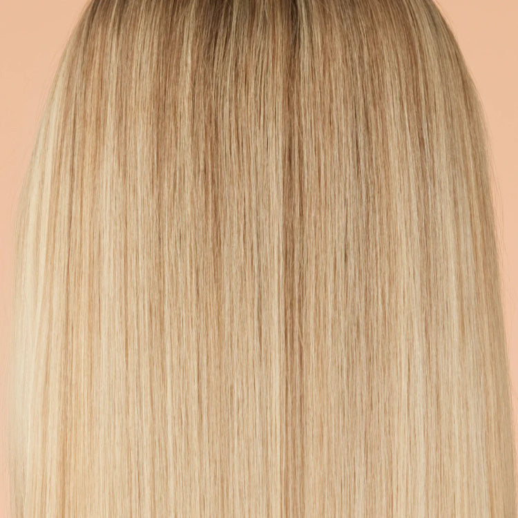 Close-up of straight blonde hair on a peach background