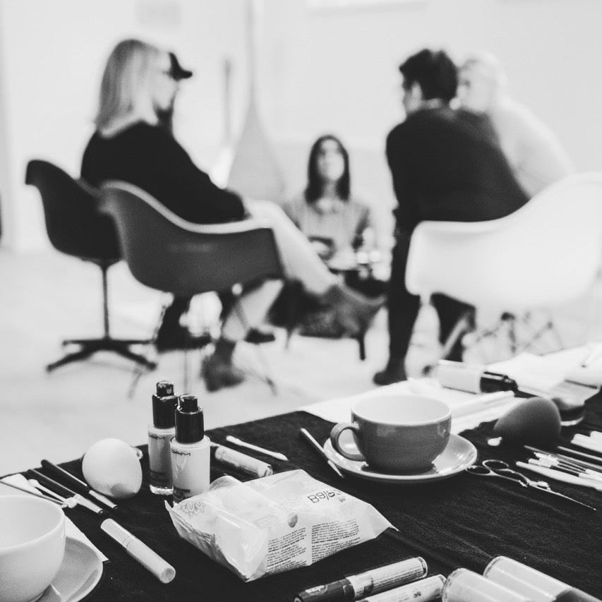 Table with makeup items and people in the background