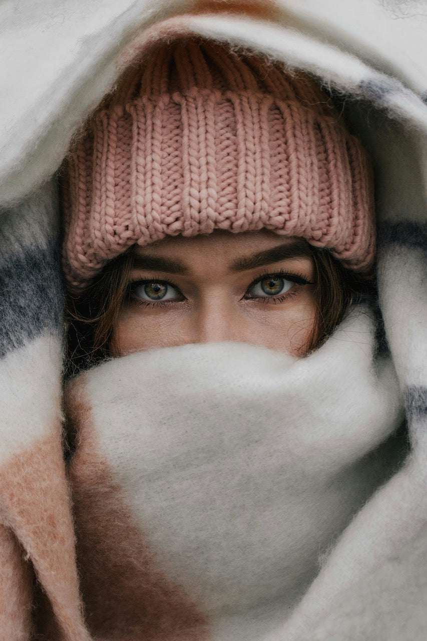 Person wearing a pink knit hat and blanket, looking directly at the camera.