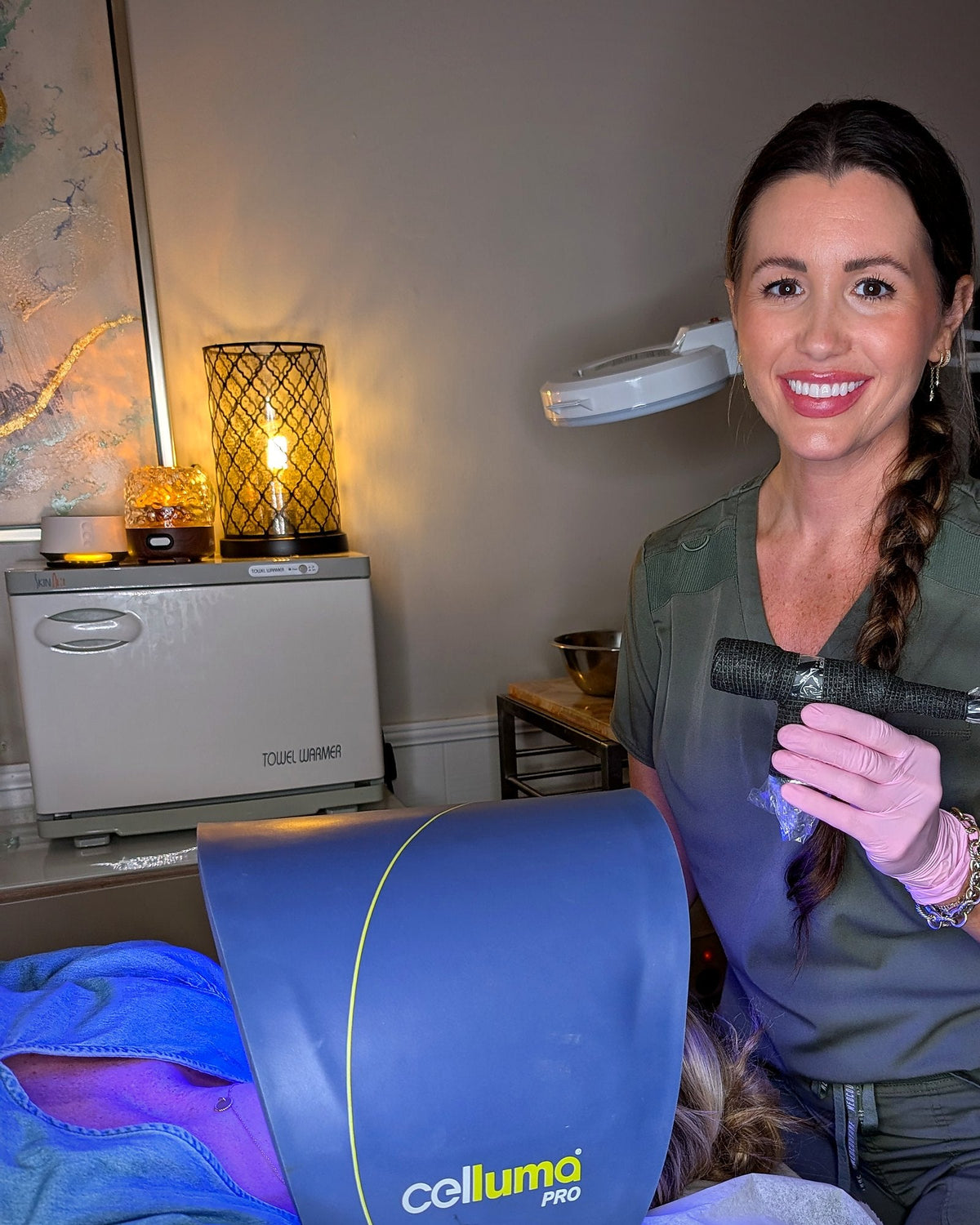 Caroline holding the ProCell microchanneling device beside a client under the Celluma LED light at Skin By Caroline in Rock Hill, SC